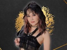 Woman with layered dark hair, wearing a black outfit and choker, against a dark background with gold accents, looking confidently.