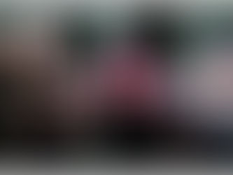 Three people in fantasy costumes with dramatic expressions in a forest. One has red wings, another wears fur, all in dark outfits.