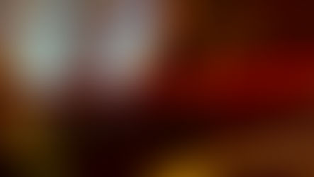 Man in a boxing ring with red gloves, standing near the ropes. Another person with a guitar in the background, stage lights create a moody ambiance.