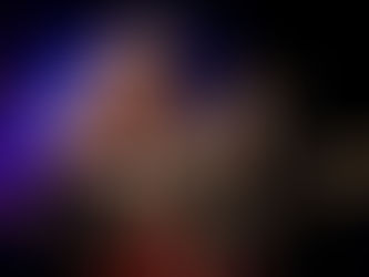 Musicians perform energetically on stage with guitars, wearing patterned outfits. Background is colorful, and lighting is vibrant.