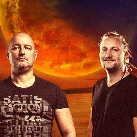 Two men pose before a fiery orange moonlit sky; the left shirt shows SATISFACTION in bold text.