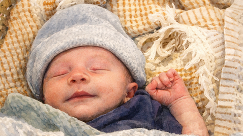 newborn sleeping with his hand raised up in a fist, like a power pump.