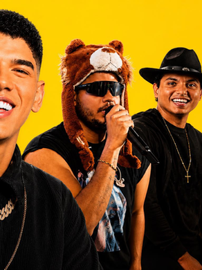 Quatro homens sorridentes em fundo amarelo; um canta ao microfone, outro usa chapéu de urso, e dois vestem chapéus de cowboy.