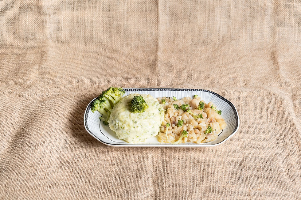 Prato com purê de batata e brócolis em um fundo de tecido bege. Purê decorado com um pedaço de brócolis. Ambiente rústico.