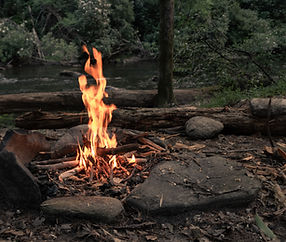 campfire-surrounded-by-greenery-rocks-with-river-forest.jpg