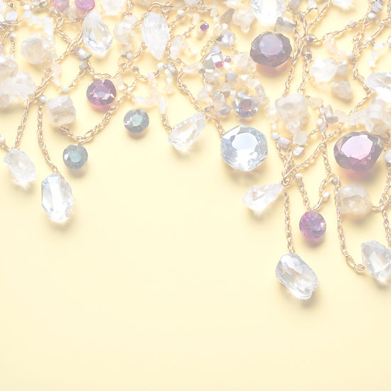A few scattered randomly placed gems and crystals and beads and chain on a very pale yell