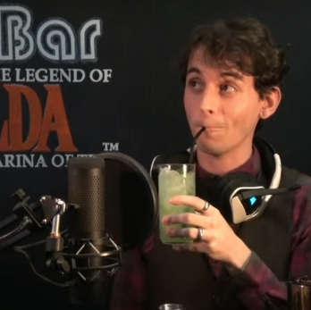 A bartender wearing headphones sips a tall green drink from a glass. The bar behind him says "Cameroxn's XBar The Legend of Zelda Ocarina of Time"