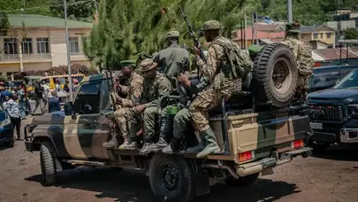 Military personnel traveling in a pickup truck in eastern DRC during ongoing conflict involving M23 rebels and the withdrawal of foreign forces from Rwanda and Uganda