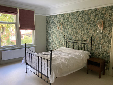 Guest bedroom with floral wallpaper and iron framed bed