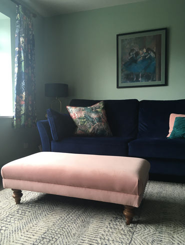 Blue sofa with pink footstool in living room