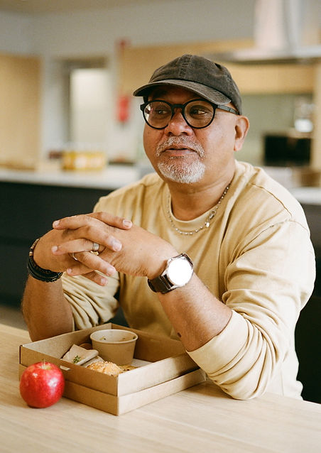 Middle-aged man wearing a cream-yellow sweater, smiling warmly