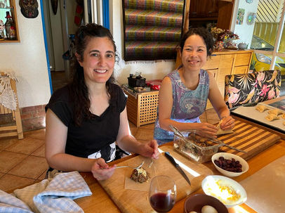 Two women preparing empanadas sitting at a table.