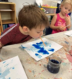 three year old painting with classmate