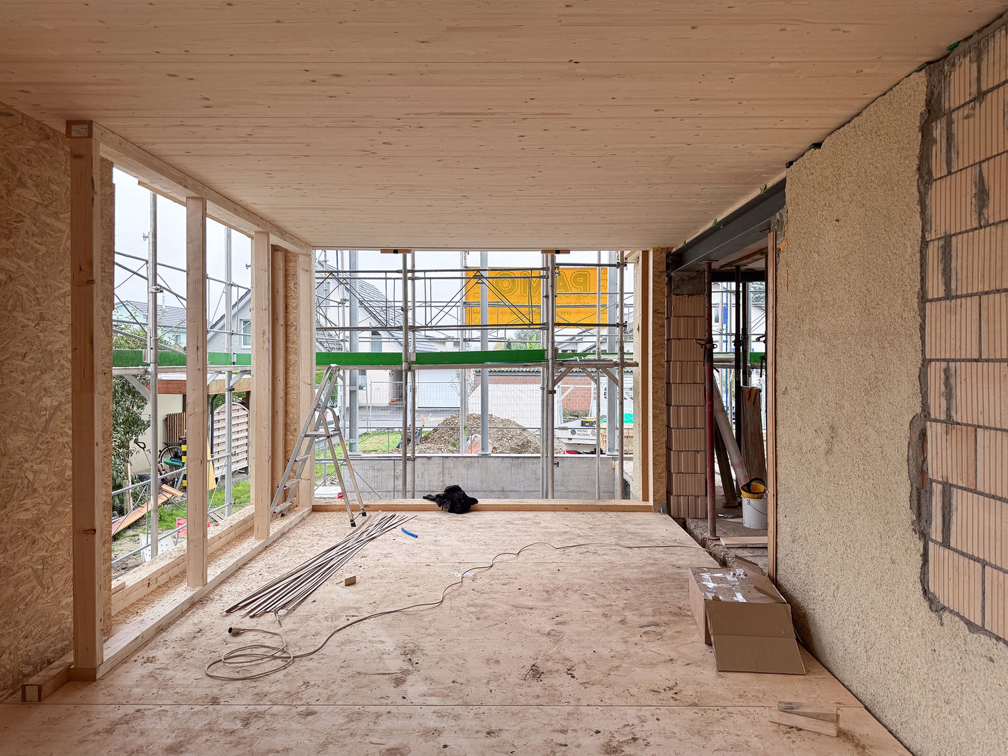 Baustellenfotografie mit Blick ins Wohnzimmer und sichtbarem Holzelementbau.