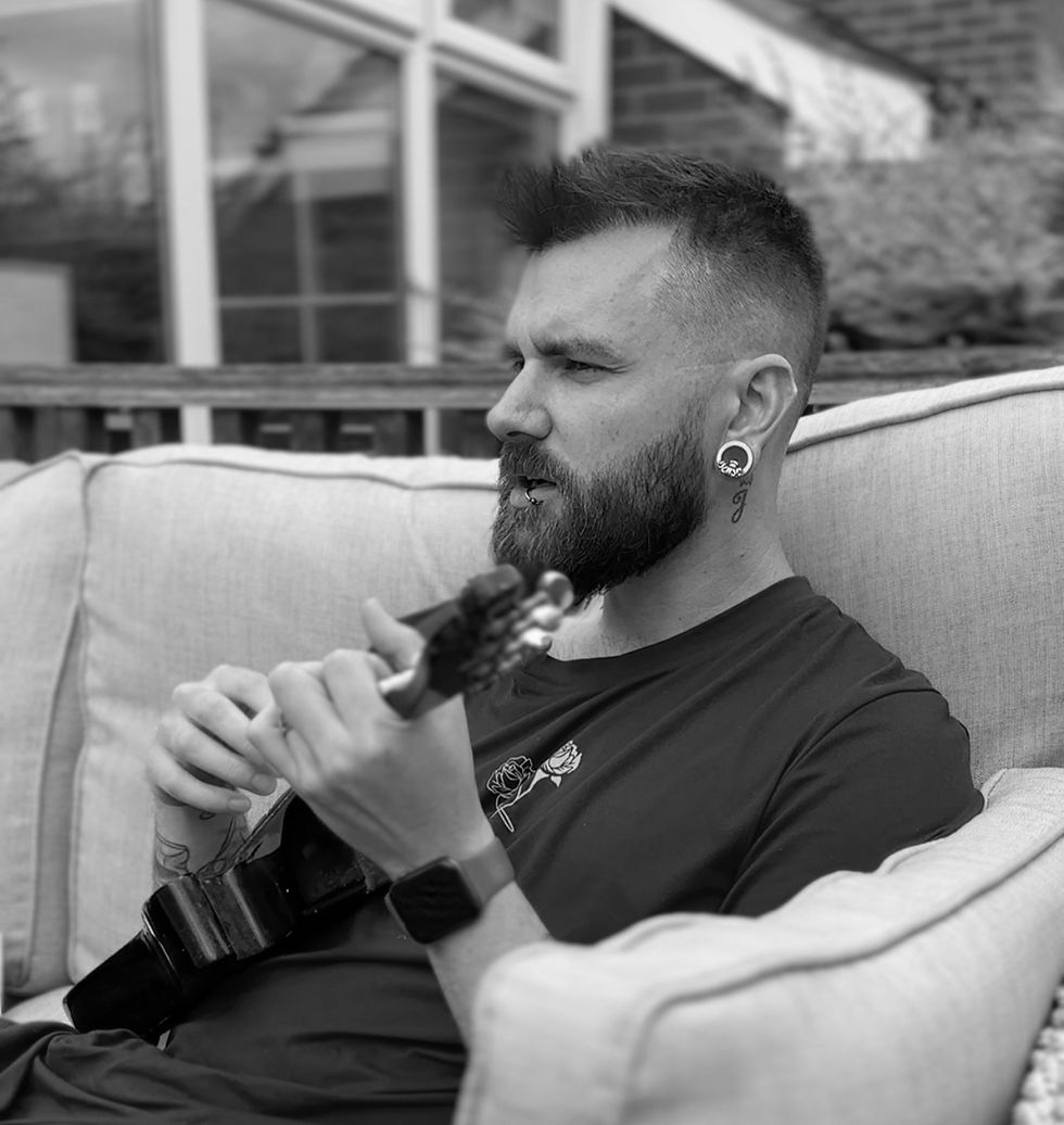 Black and white image of author Tom Dineen playing a ukulele outside in the summer.