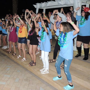 Students dancing in leis at a festival beach party