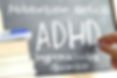 Hand writing on a blackboard in a class with the word ADHD written on