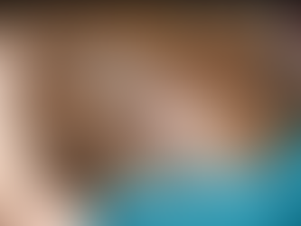 Veterinarian in teal scrubs using a stethoscope to examine the flank of a chestnut horse