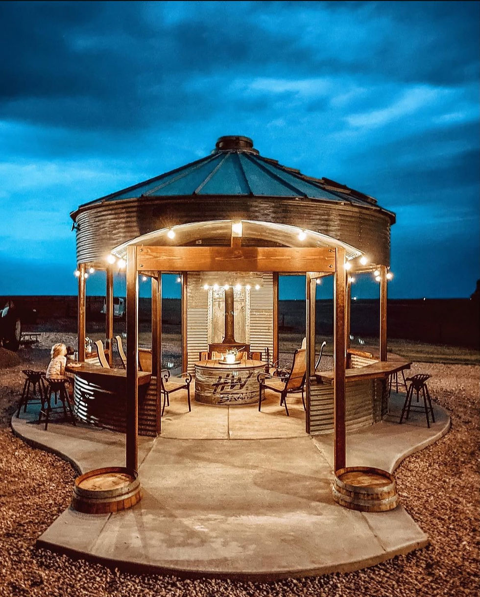 A custom retro grain bin silo converted into a gazebo on a concrete slab with lighting and a fireplace installed by Building Solutions of Spicewood, a Texas Innovative Building Solutions company