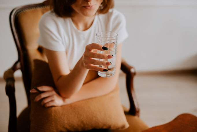 Woman holding glass of water while sitting in chair