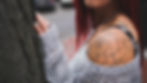 Woman with tattoos leaning against a tree