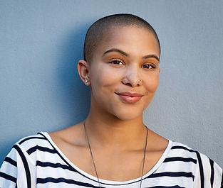 Woman with shaved head and a nose piercing smiling at the camera