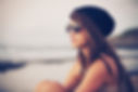 girl wearing sunglasses sitting outside by the water