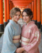 Two Western women wearing pastel kimono beneath red torii gates