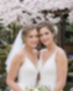 Two Western brides beneath cherry blossoms in a Japanese garden