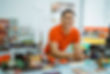 handsome-male-shopkeeper-smiles-camera-while-leaning-minimarket-cash-register.jpg