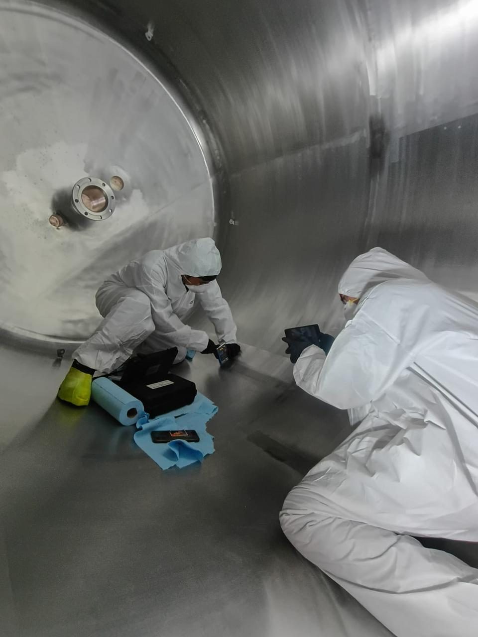 Inspectores con traje de protección revisando el interior de un tanque sanitario
