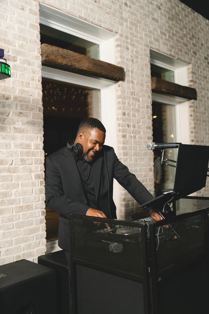 Wedding DJ smiling while performing behind the DJ booth.