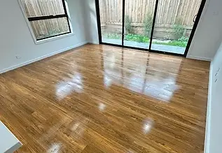 Empty room showcasing defect-free handover cleaning standards on high-gloss polished hardwood flooring.