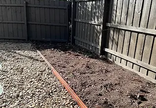 WDCommercial programmed exterior grounds care and commercial garden maintenance showing clean timber perimeter boundary fencing, a freshly cleared soil border edge, and structured landscape gravel aggregates.