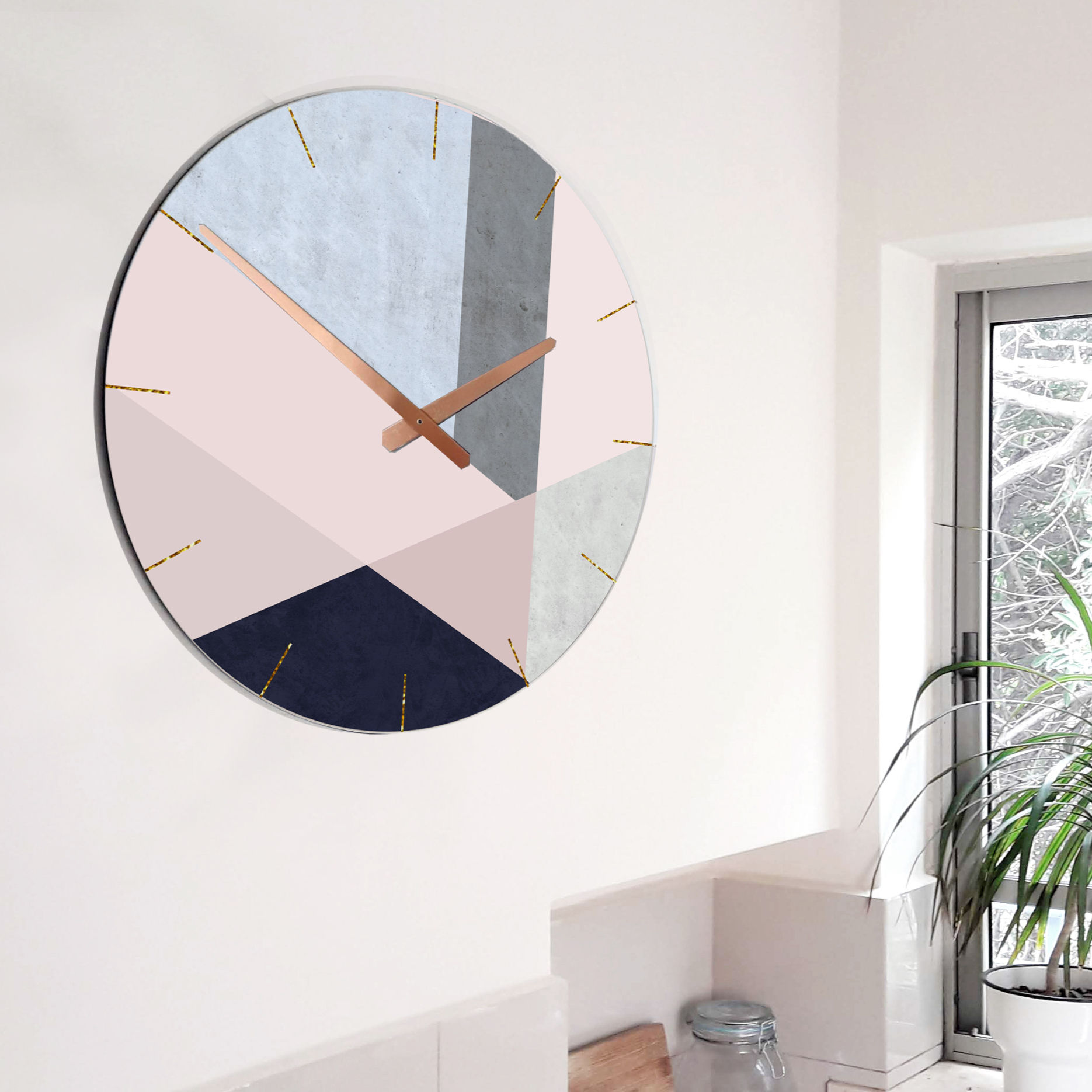שעון קיר עגול עם עיצוב גיאומטרי בגוונים של פודרה, אפור ותכלת, עם מספרים לבנים ומחוגים מוזהבים, על רקע קיר לבן וחלון
