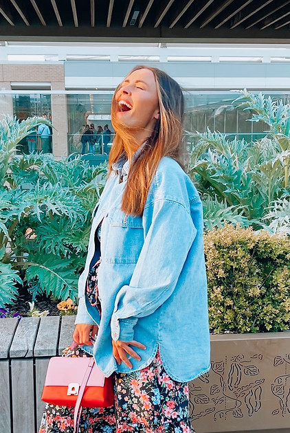woman laughing at a terrace bar, wearing denim shacket
