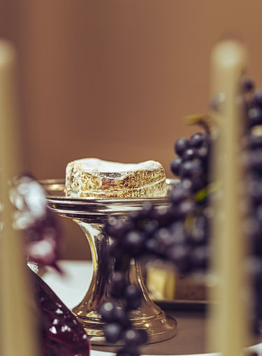 Soft cheese on a pedestal surrounded by grapes – refined cheese display