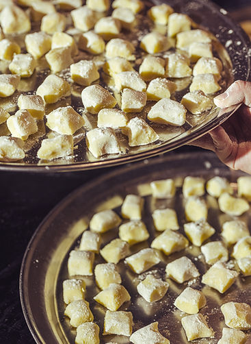 Close-up of hand plating homemade gnocchi – behind the scenes of a luxury event