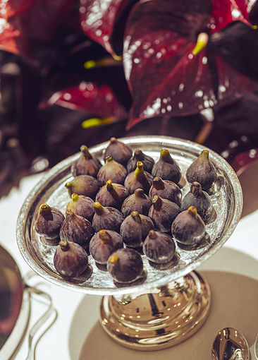 Fresh figs on a silver platter with red tropical foliage – high-end buffet setup