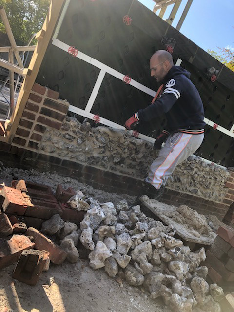 bricklayer building flint stone barn with red brick coins and archways