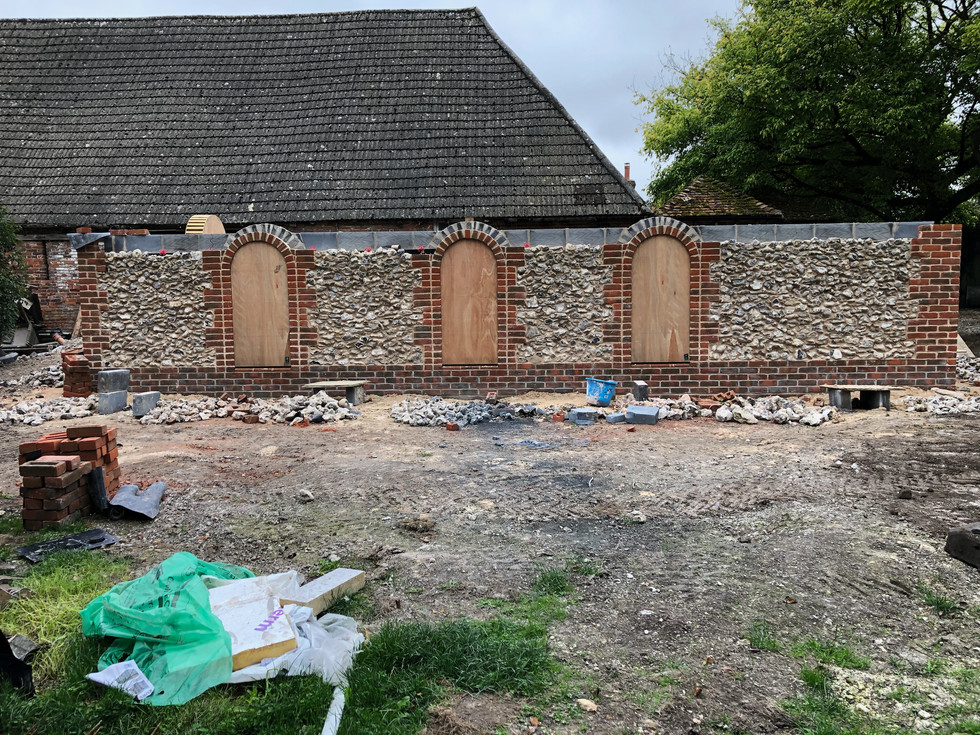 traditional build barn using red reclaimed bricks and locally sourced flint. adding features like brick coins on corners and archways for window openings