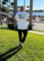A person wearing a 'Team Rocco' shirt with text on the back reading 'Team Rocco Don’t MS with us,' walking near a waterfront