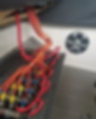 Close-up of tangled red and orange electrical wires in a boat-like compartment, with a round vent on a white wall nearby.