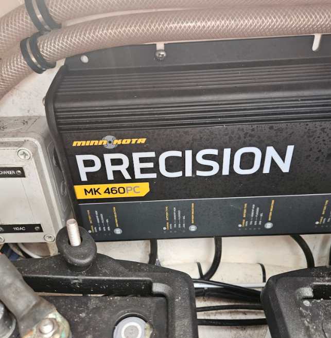 Minn Kota PRECISION MK 460PC charger mounted in a boat compartment, with hoses, wires, and dusty black battery trays visible