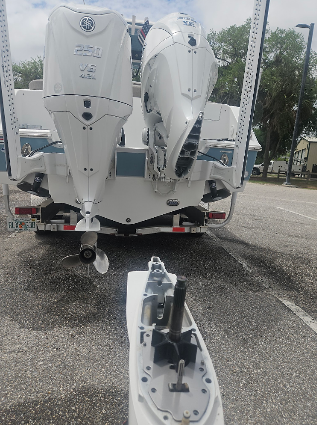 Twin outboard boat undergoing marine electronics inspection and service at boat ramp.