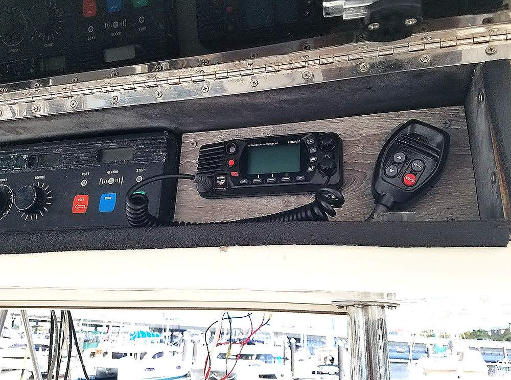 Mounted marine VHF radio with microphone and other control panels installed in the boat's dashboard.