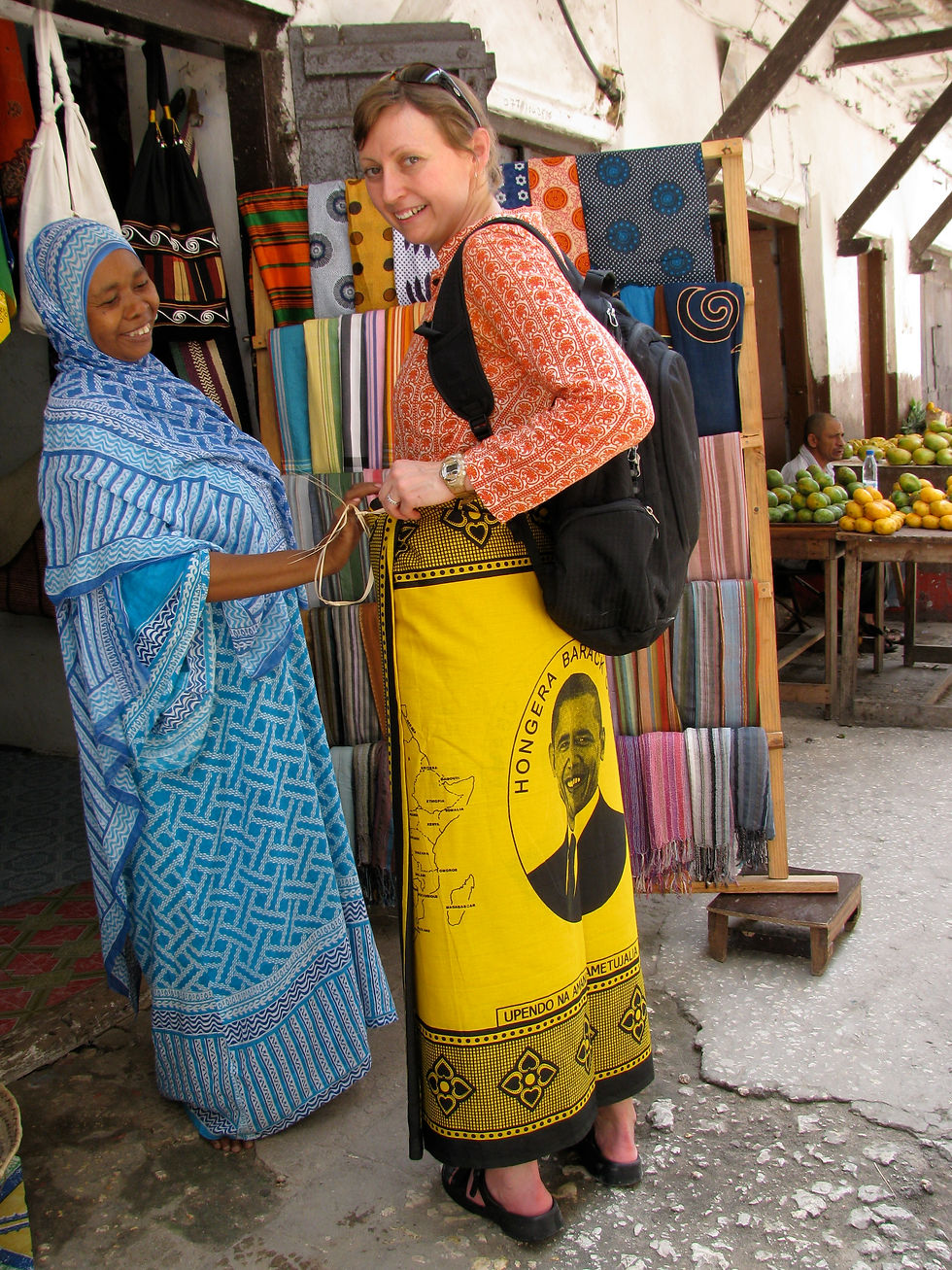 A saleswoman smiles as she wraps me in a kanga that features the face of Barack Obama on my backside.