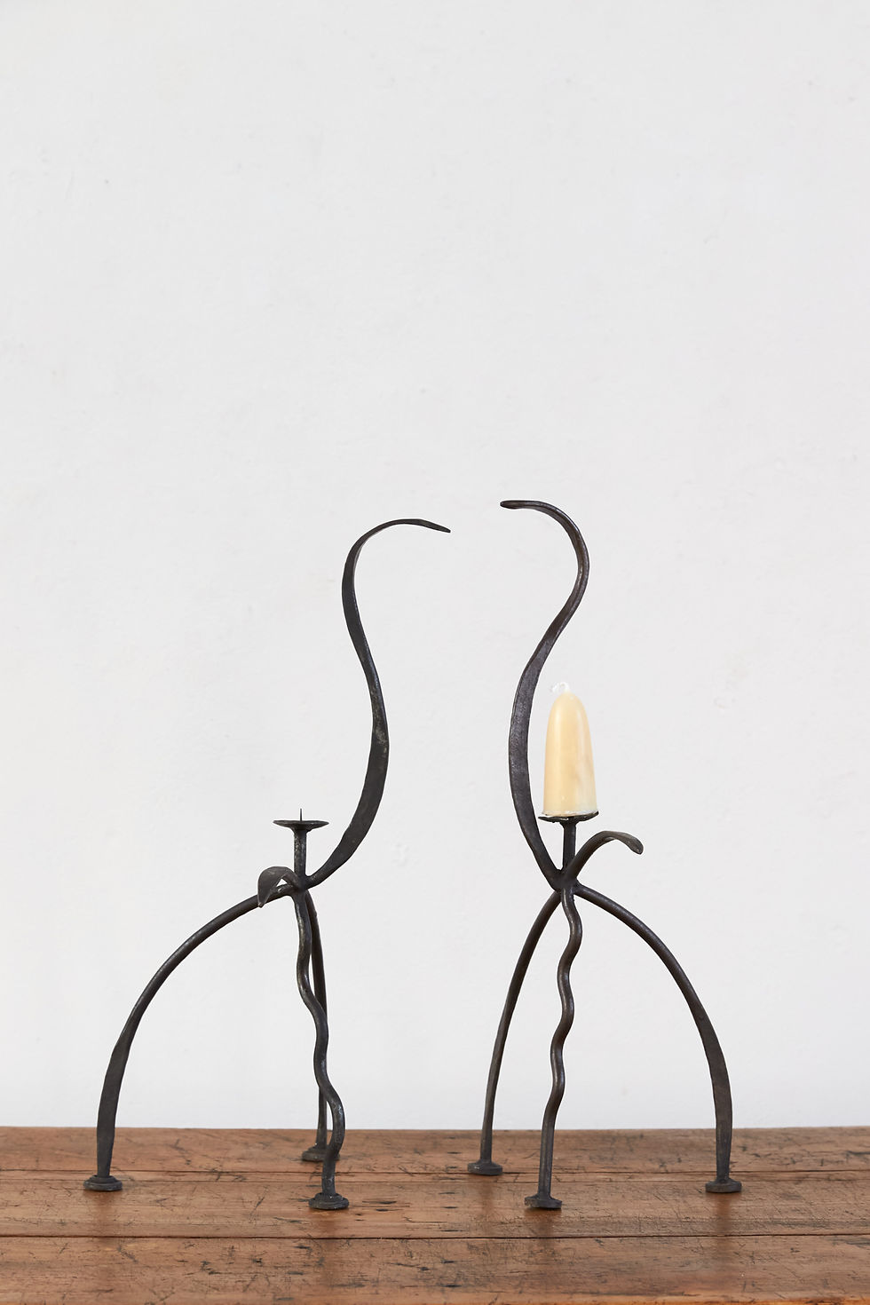 A hand-forged vintage iron pricket candleholder with a distinctive bird-like silhouette.