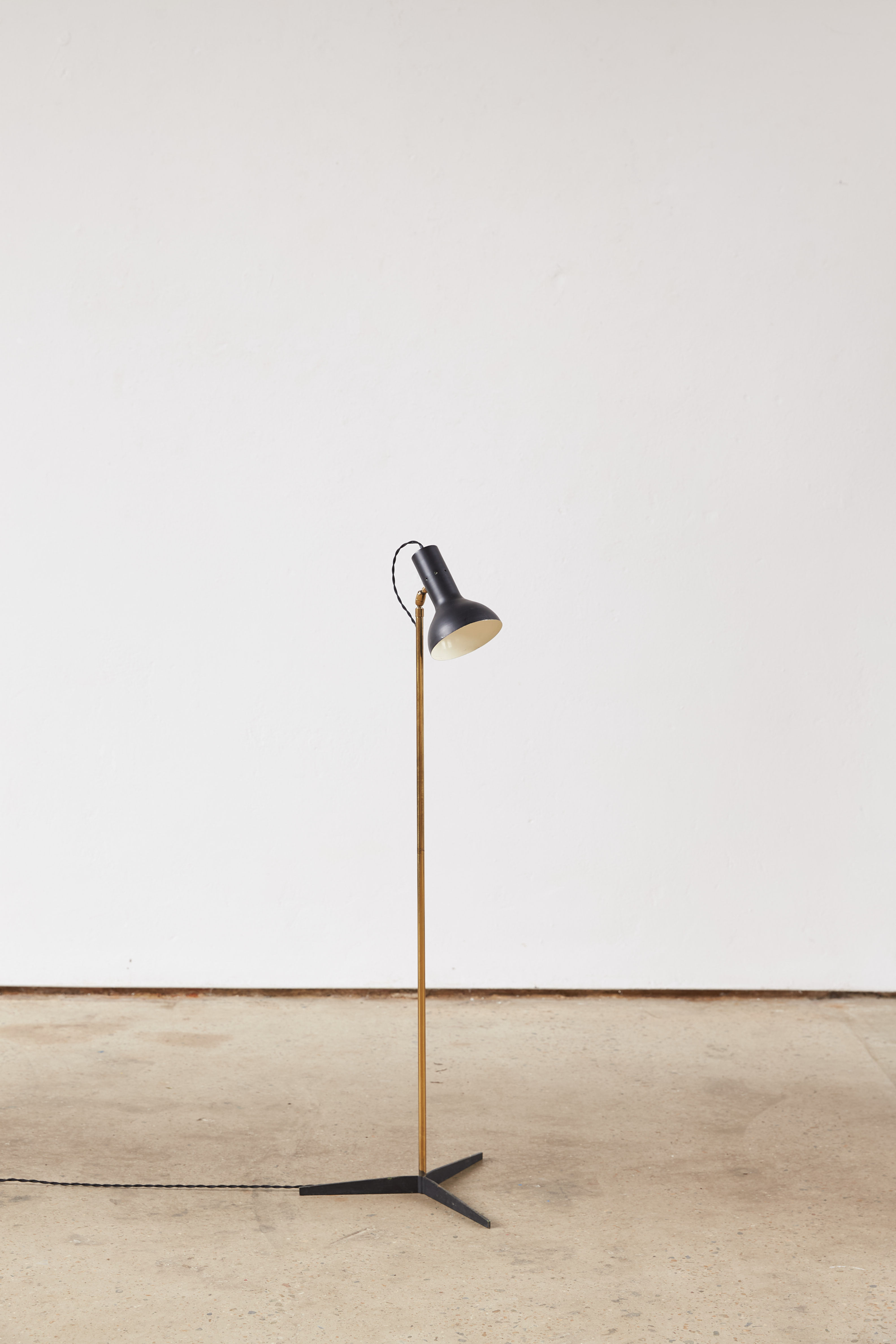 A refined 1950s Italian reading lamp, featuring a slender brass stem, black metal tripod base and adjustable black spun alumi