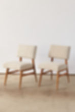 A pair of French mid-century chairs dating from around 1950, with elegant wooden frames and generously proportioned seats and